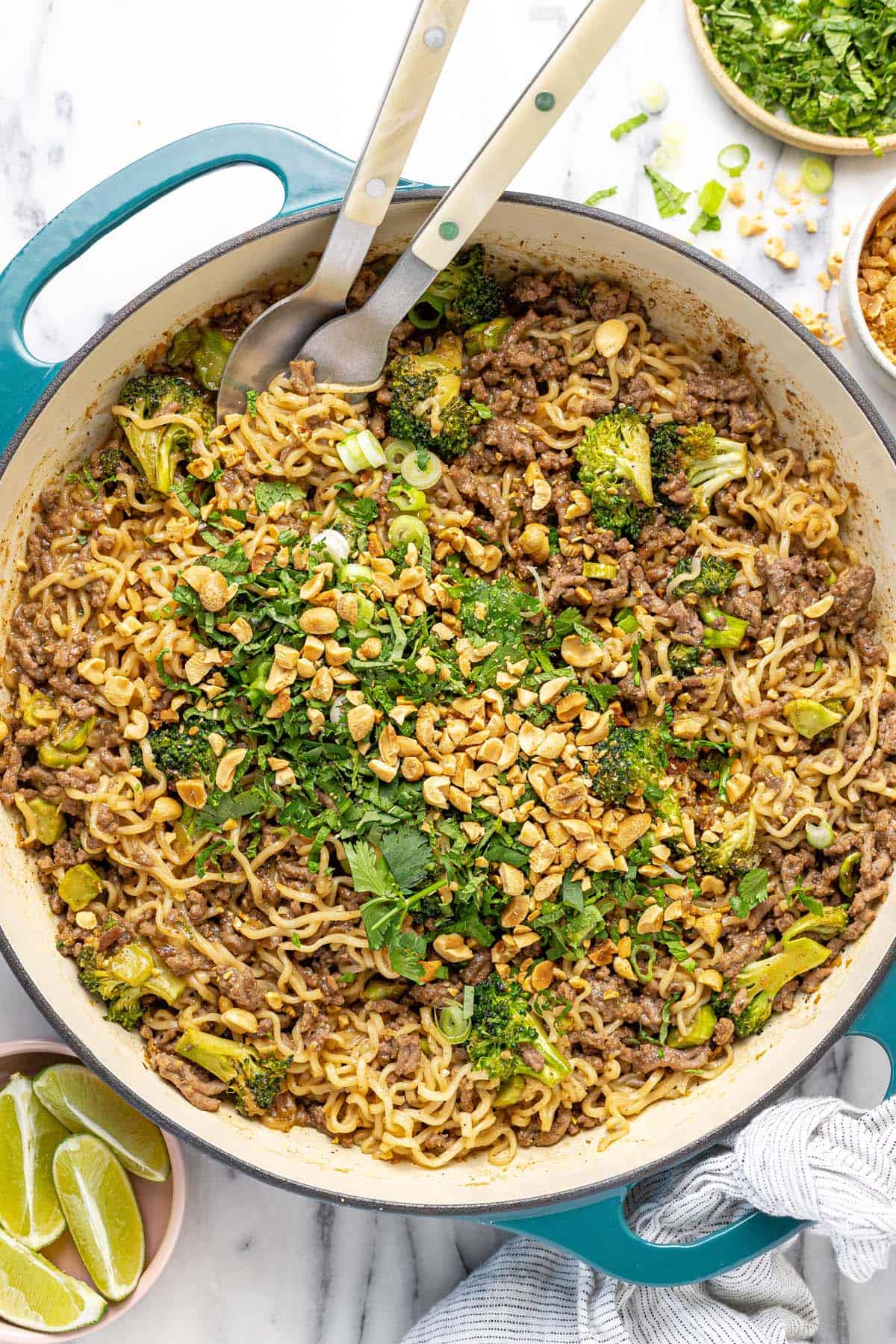 Large pan filled with sesame ginger ground beef and peanut noodles topped with herbs.