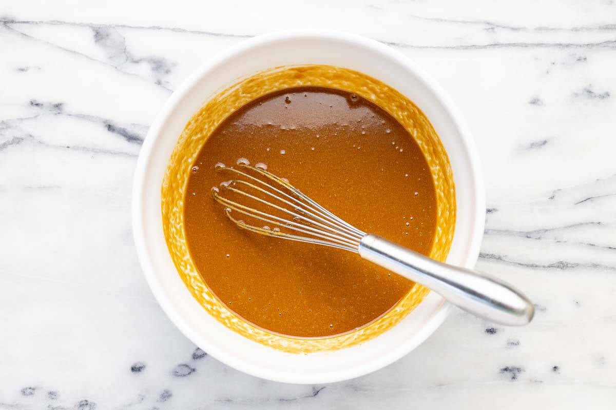 Bowl of peanut dressing with a whisk.