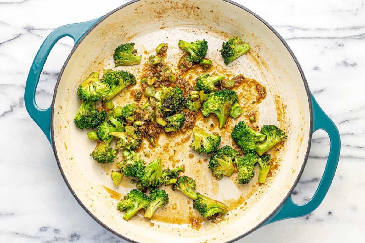 Large pan filled with sauteed broccoli, garlic, and ginger.