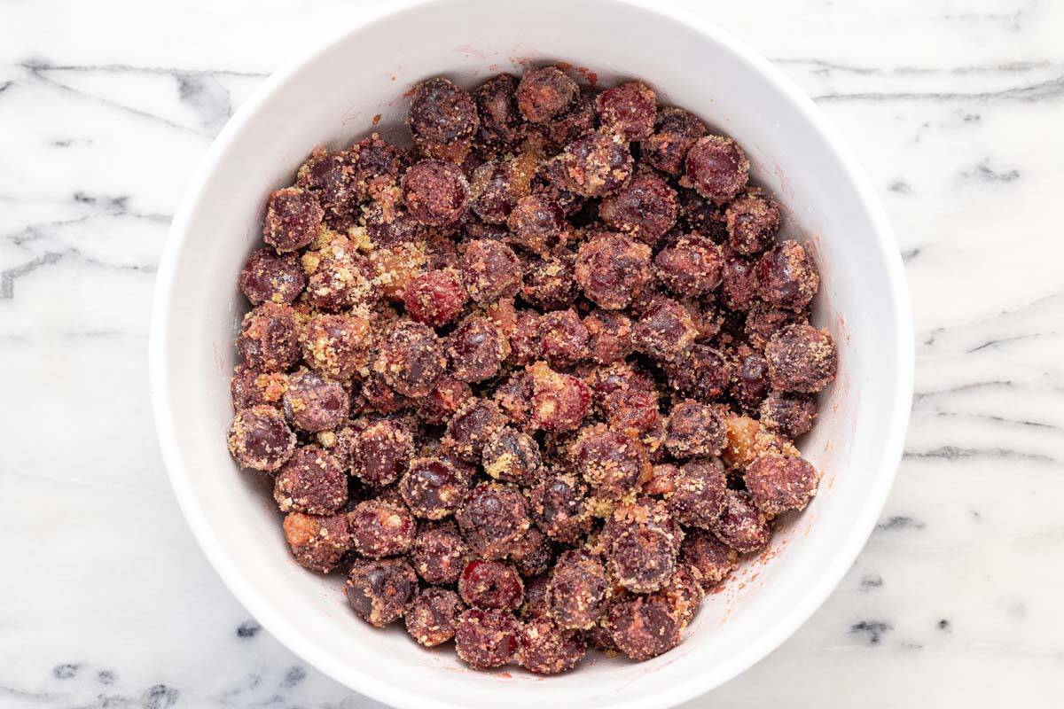 Large bowl filled with cherries tossed in sugars, cornstarch, and lemon juice.