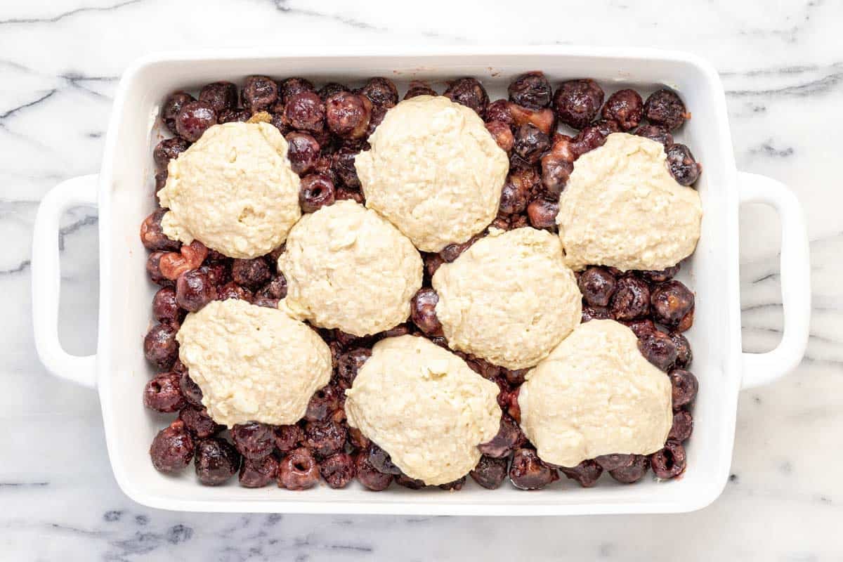 Large baking dish filled with cherry cobbler ready to go in the oven.