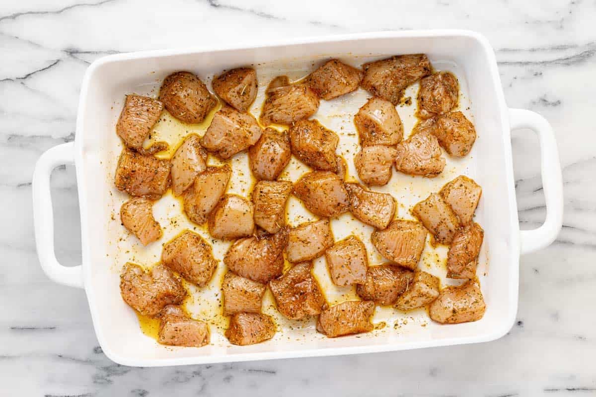 Large baking dish filled with seasoned, cubed chicken breast.