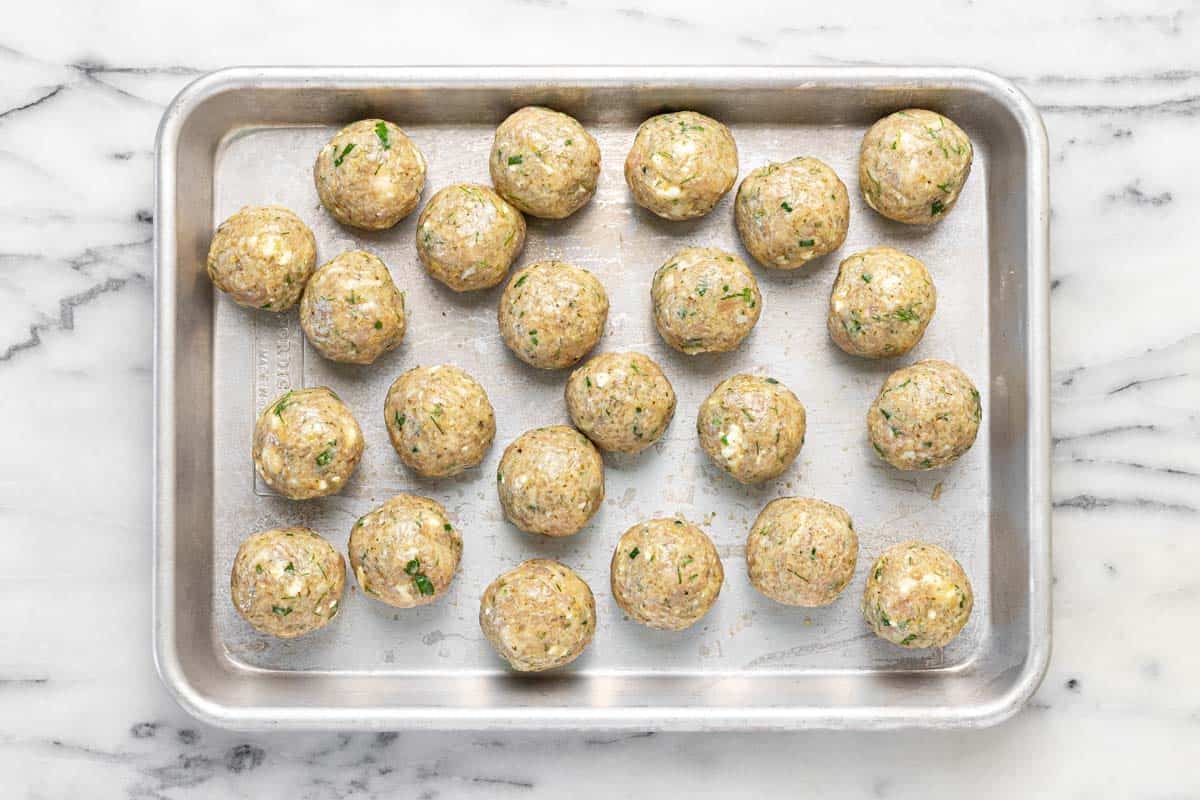 Raw chicken meatballs on a small sheet pan.