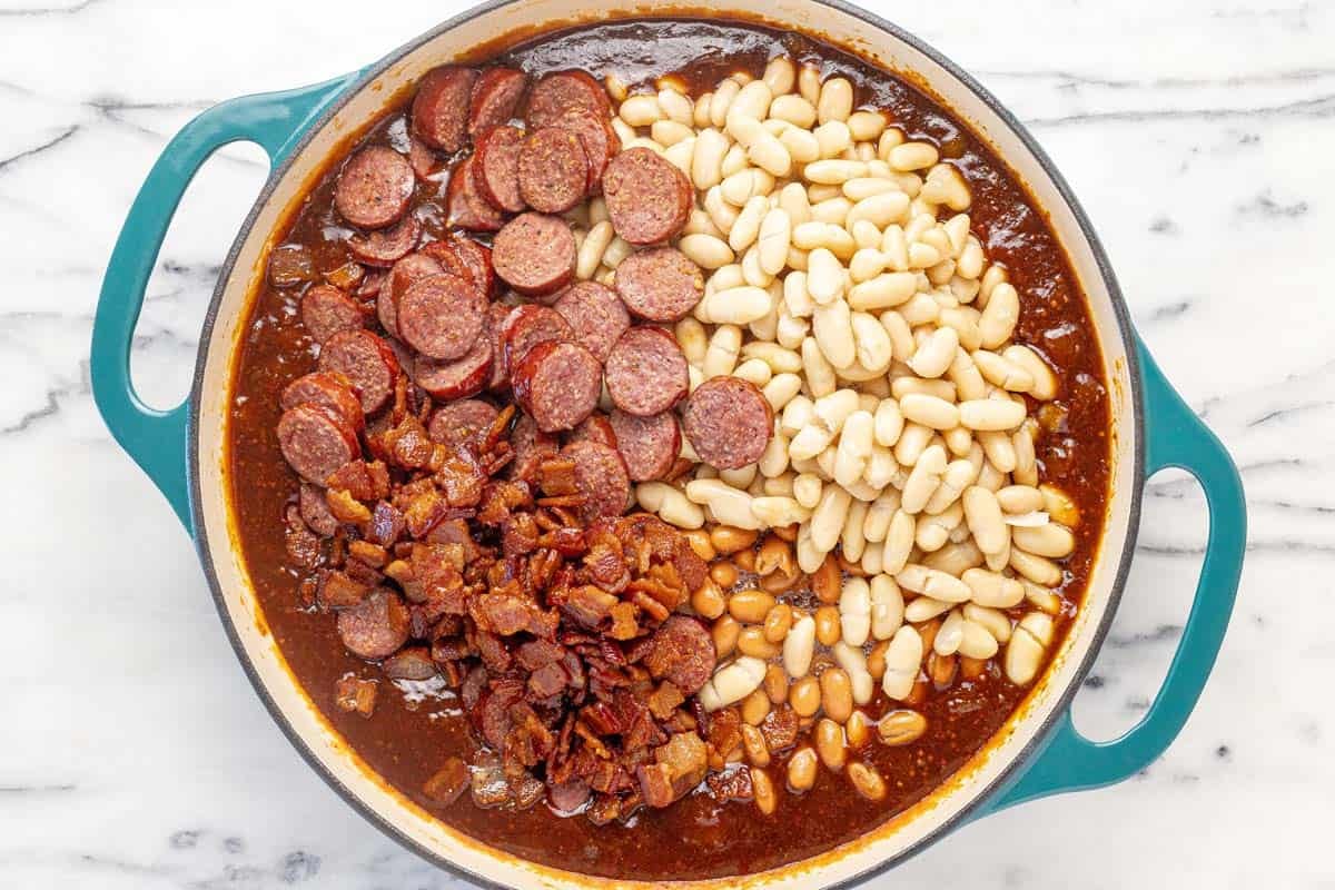 Bacon, sausage, beans, and sauce in a large pan for baked beans.