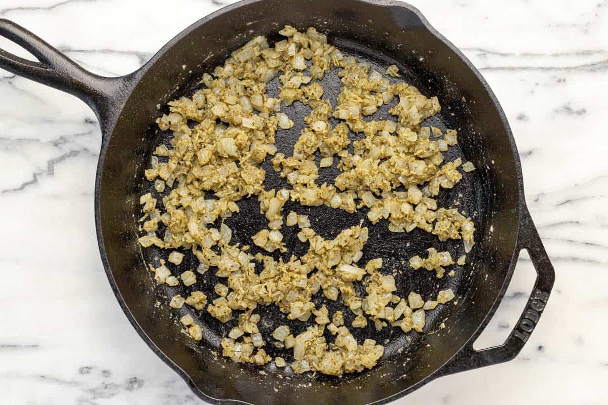 Large skillet filled with sauteed onions, garlic, and herbs.