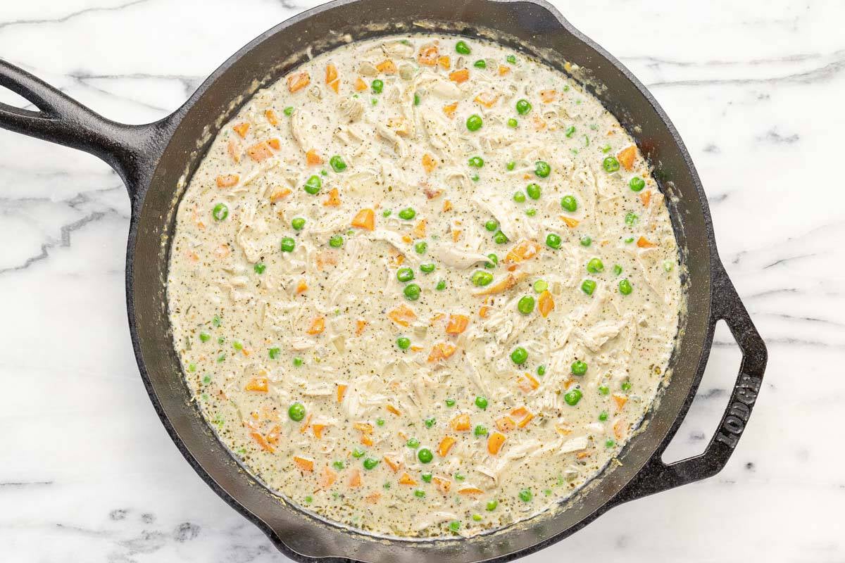 Chicken pot pie filling in a large cast iron skillet.