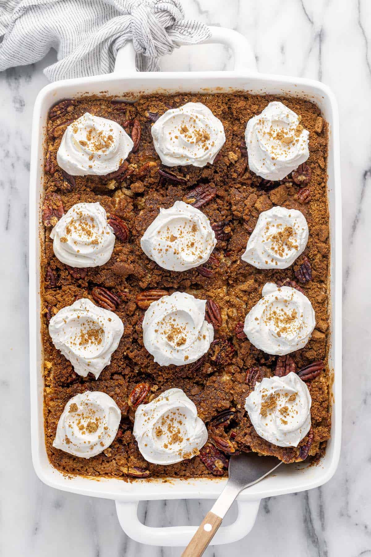 Large pan filled with pumpkin dump cake topped with Cool Whip.