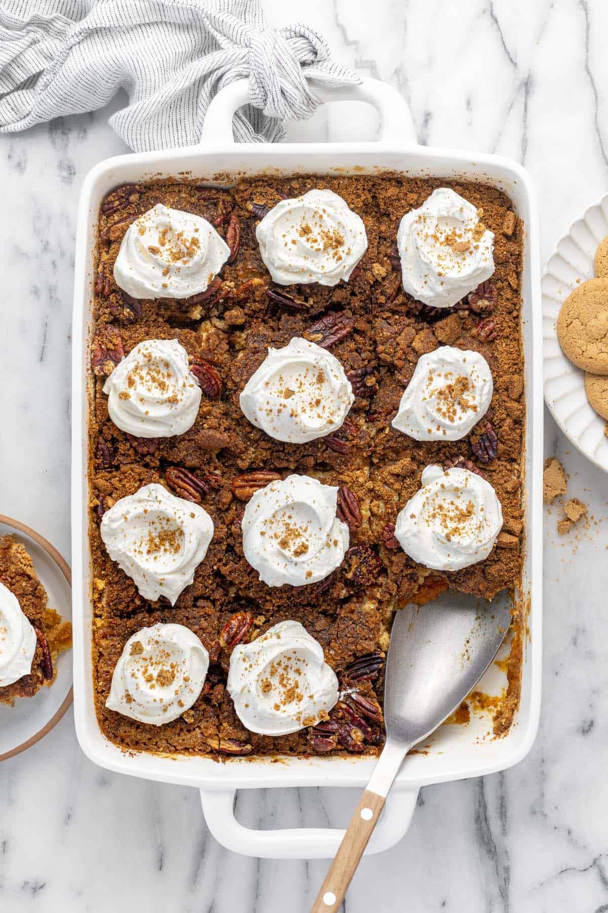 Large pan filled with pumpkin dump cake topped with Cool Whip. 