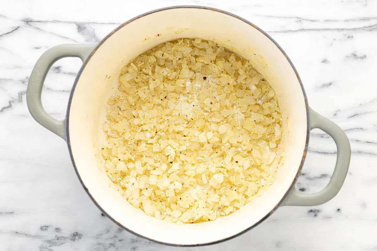 Large pot filled with sauteed onions and garlic.